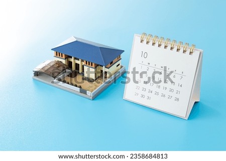 House model and calendar on blue background.