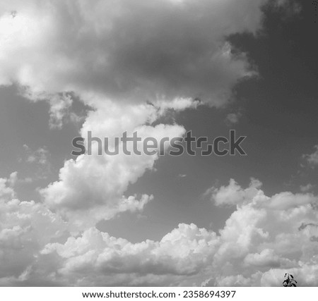 High cumulus clouds paint the sky in monochrome strokes, a celestial canvas of serene grandeur. Nature's whispers echo in their billowy embrace Royalty-Free Stock Photo #2358694397