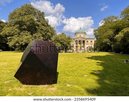 Purple cube on the background of a park and an old mansion on a sunny summer day