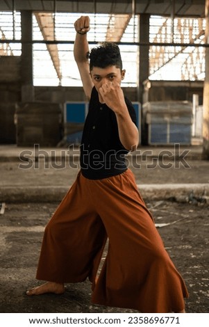an Asian man posing fist in front of an old building alone during the day
