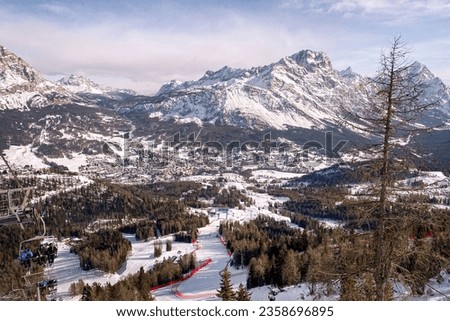 Scenic view of Tofana ski racing slope in Cortina d'Ampezzo in Italy against snow covered Punta Sorapiss Mountain and blue sky Royalty-Free Stock Photo #2358696895