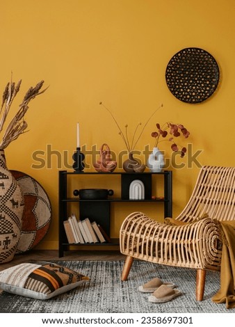 Warm composition of yellow living room interior with black ornament on wall, black sideboard colorful pillows, baskets, stylish armchair and personal accessories. Home decor. Template. Royalty-Free Stock Photo #2358697301