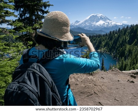 Woman taking smartphone photos of snow-capped Mount Rainier from Summit Lake Trail. Mt Rainier National Park. Washington State. Royalty-Free Stock Photo #2358702967