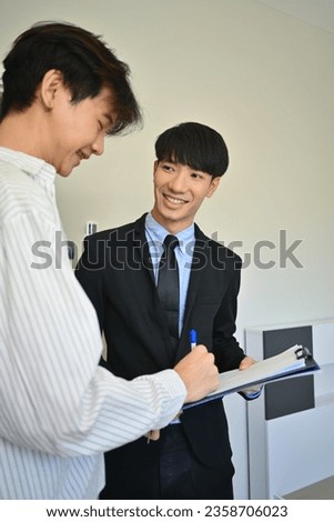 Happy young asian man signing contract with realtor. First property purchase, ownership and real estate concept