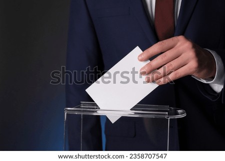 Man putting his vote into ballot box on dark background, closeup. Space for text