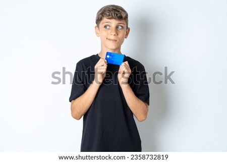 Photo of cheerful beautiful kid boy wearing casual black T-shirt hold debit card look empty space