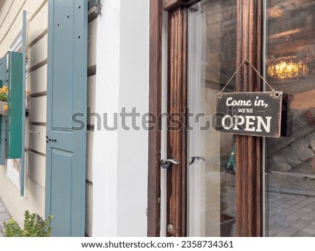 open sign, vintage come in we are open entrance sign hanged on a window door of a small shop or store. entrance of a cafe or shop with sign. small business concept background