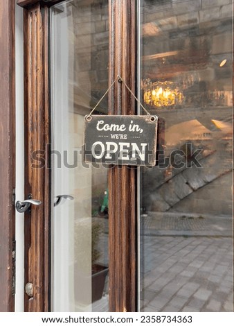 open sign, vintage come in we are open entrance sign hanged on a window door of a small shop or store. entrance of a cafe or shop with sign. small business concept background