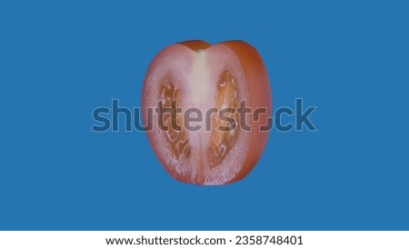 Healthy fruits and vegetables creative concept. Closeup studio shot of tomato round slice isolated on blue background.