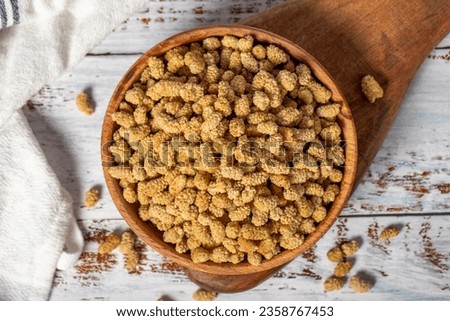 Dried mulberries in wooden bowl. Sun-dried mulberry on a white wood background. Top view Royalty-Free Stock Photo #2358767453
