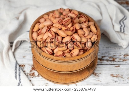 Pistachios in wooden bowl. Pistachios on white wood background. Close up
