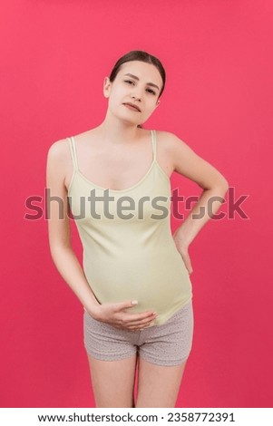 Pregnant woman with a pain in her back on colored Background isolated.