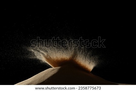 Deep impact on sand hill and splash all over area. Sand dune hill over wind storm and blast dust splash over mountain. Sunshine rain fall on sand hill wind blow. Black background isolated