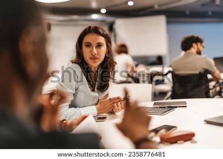 Diverse coworkers brainstorm at table in modern office at work, discussing work, sharing knowledge and learning new things. Royalty-Free Stock Photo #2358776481