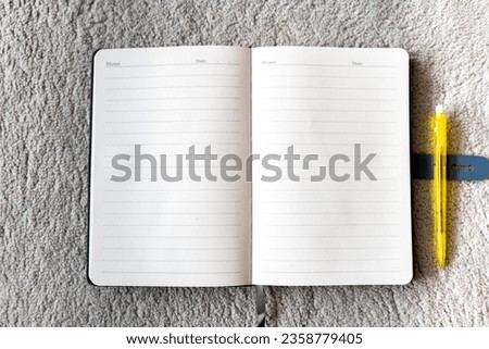 Note Book on grey carpet, Note Book with a pen, copy space on notebook , Yellow pen with Copy space notebook.