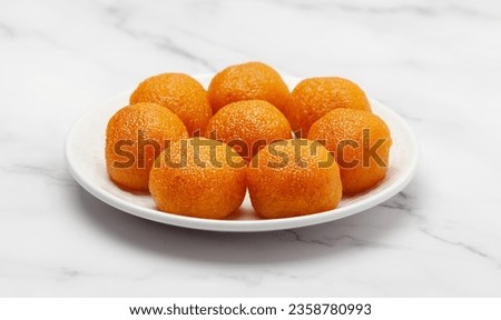 Close-up of an Indian Sweet "Motichoor Ladoo" also Called Boondi Ladoo on a white ceramic plate. Isolated on a Marble background. Front view. Royalty-Free Stock Photo #2358780993