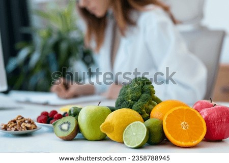 Close up of beautiful smart nutritionist woman working with computer while taking notes in the nutritionist consultation Royalty-Free Stock Photo #2358788945