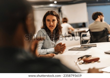 People working in a positive atmosphere at the office, discussing, having fun conversation and smiling. Royalty-Free Stock Photo #2358795619