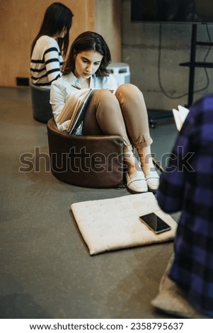 Start-up female employee working on a new project with her teammates around her. Royalty-Free Stock Photo #2358795637