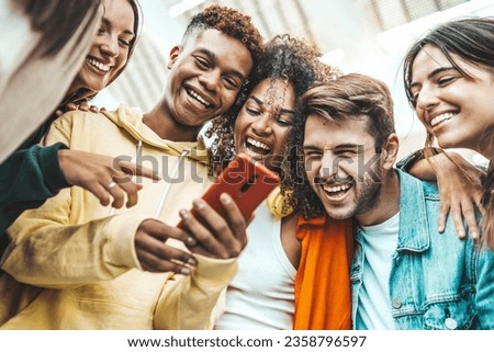 Multiracial young people using smart mobile phone device outdoors - Happy teenagers watching funny reel on smartphone - Technology life style concept Royalty-Free Stock Photo #2358796597