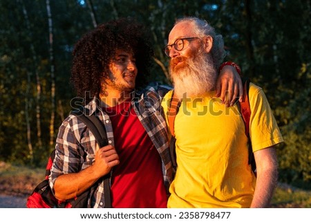 This heartwarming image captures the strong bond between generations. An adult half-Arabic son shares a moment of laughter and affection with his senior father while hiking in the great outdoors. It's Royalty-Free Stock Photo #2358798477