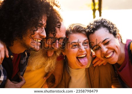 Happy young group of multiracial best friends having fun together outdoors. Millennial diverse people enjoying time together taking selfie portrait in a natural setting. High quality photo