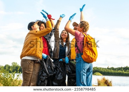 Celebrate the spirit of environmental stewardship and camaraderie in this dynamic image. A diverse group of young volunteers from different ethnic backgrounds unite to clean up the forest. With high Royalty-Free Stock Photo #2358798485