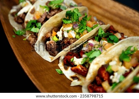 A selective focus closeup of Mexican tacos on a wooden plate