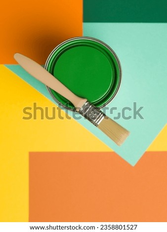 can of green paint and brush on colourful geometrical background