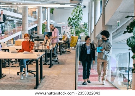 In a modern startup office, a diverse group of young professionals collaboratively tackles various business problems and challenges, surrounded by their engaged colleagues, fostering innovation and Royalty-Free Stock Photo #2358822043