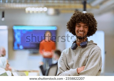 In a modern office environment, an African American young entrepreneur with headphones engages in work, while in the background, his dedicated colleagues exemplify teamwork and collaboration