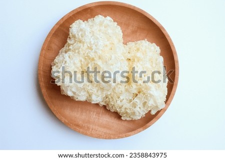 Dried white fungus on wooden plate, isolated on white background