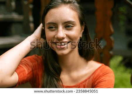 In a close-up street shot, a captivating young lady showcases her long brunette hair and an alternative aesthetic characterized by a charming tooth gap. She flashes a radiant smile Royalty-Free Stock Photo #2358845051