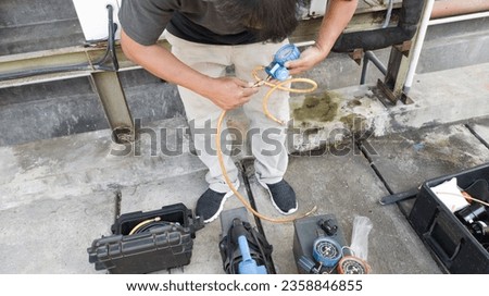 An air conditioning technician uses his equipment to carry out air conditioning repairs. 
