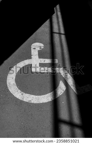 A grayscale closeup shot of a wheelchair symbol on the floor with shadows
