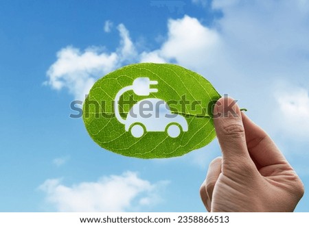 Hand of human is holding green leaf with EV Electric Vehicle, renewable energy carbon reduction and environment sustainable concept.