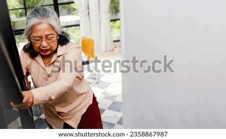 Elderly Asian woman in frail health, stroke sick, staggering, headache dizzy walking up the stairs of the house, hand touching the railing for protection or falling downstairs : Health care concept