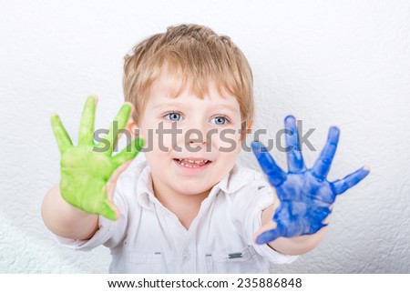 Funny kid child having fun with making handpaints with colors at home. Creative leisure for family and kids.