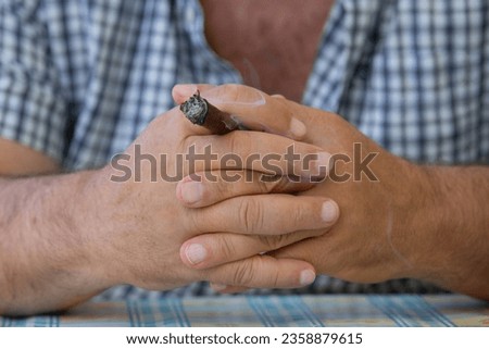 Hands of a man holding a cigar Royalty-Free Stock Photo #2358879615