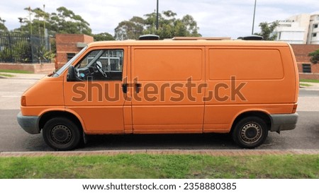 side view of orange Volkswagen van parked on street