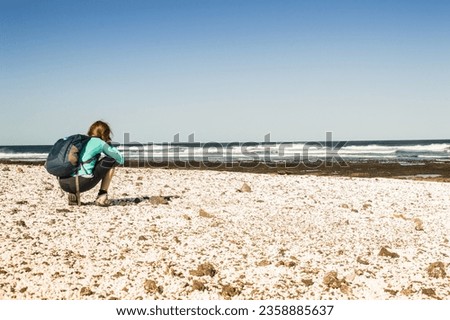 A photographer on a volcanic beach in Fuerteventura, Spain
