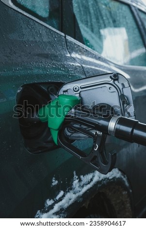 gas pump nozzle in car's fuel tank. Royalty-Free Stock Photo #2358904617