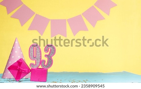 Date of birth for a girl  93. Copy space. Birthday in pink shades with a yellow background. Decorations with numbered candles and a gift box. Anniversary card for a woman Royalty-Free Stock Photo #2358909545
