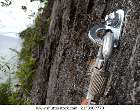 A carabiner is attached to a cliff safety anchor to support sport climbing activities