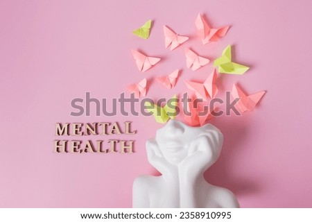 A figurine of a head with butterflies on a pink background. Mental health concept. Royalty-Free Stock Photo #2358910995