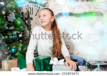 Cheerful girl with presents looking at Christmas tree