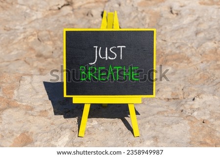 Just breathe and psychological symbol. Concept words Just breathe on beautiful black chalk blackboard on a beautiful stone background. Business psychological and Just breathe concept. Copy space