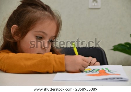 Cute little preschooler child drawing at home. girl painting a picture with school supplies, preschool child painting, drawing, child doing homework. Occupation and development for children.