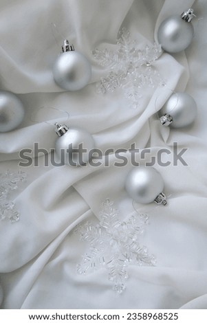 Silver Christmas ornaments on white fabric, flat lay image of holiday decoration items, silver balls, Christmas stars, plastic, glass, metal ornaments, no people, minimalistic calm atmosphere, classy