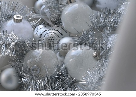 Different types of Christmas ornaments behind white curtain, silver balls, glass balls for Christmas tree decoration, no people, flat lay image on white fabric, calm minimalistic atmosphere, winter